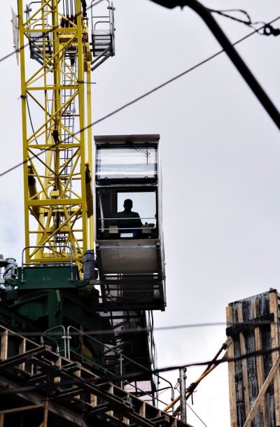 man sitting on crane tower